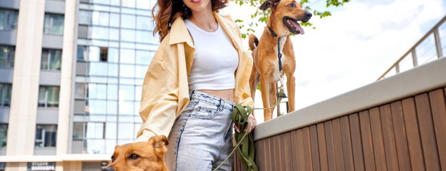 A young woman outside a city building with two dogs