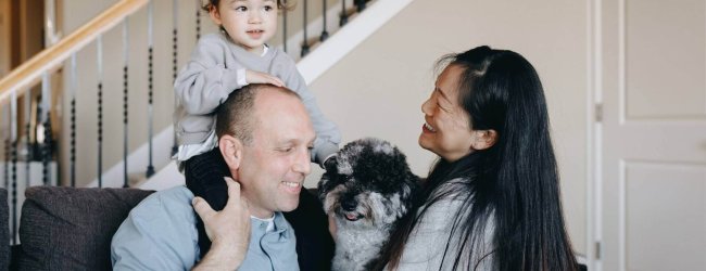 man woman, child and dog sitting on a couch