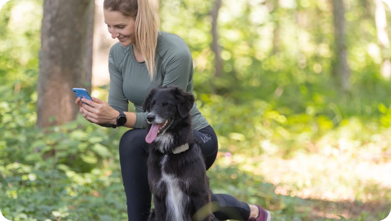 Dog sitting next to parent getting ready to run with Tractive GPS Tracker for dogs