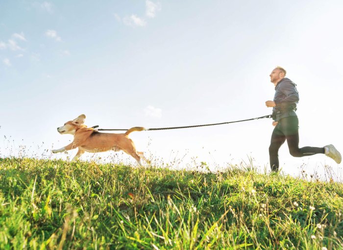 uomo corre all'aperto portando un cane al guinzaglio