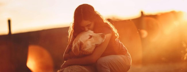 A woman hugging a dog outdoors