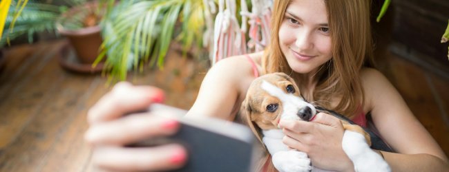 A girl taking a selfie with her puppy