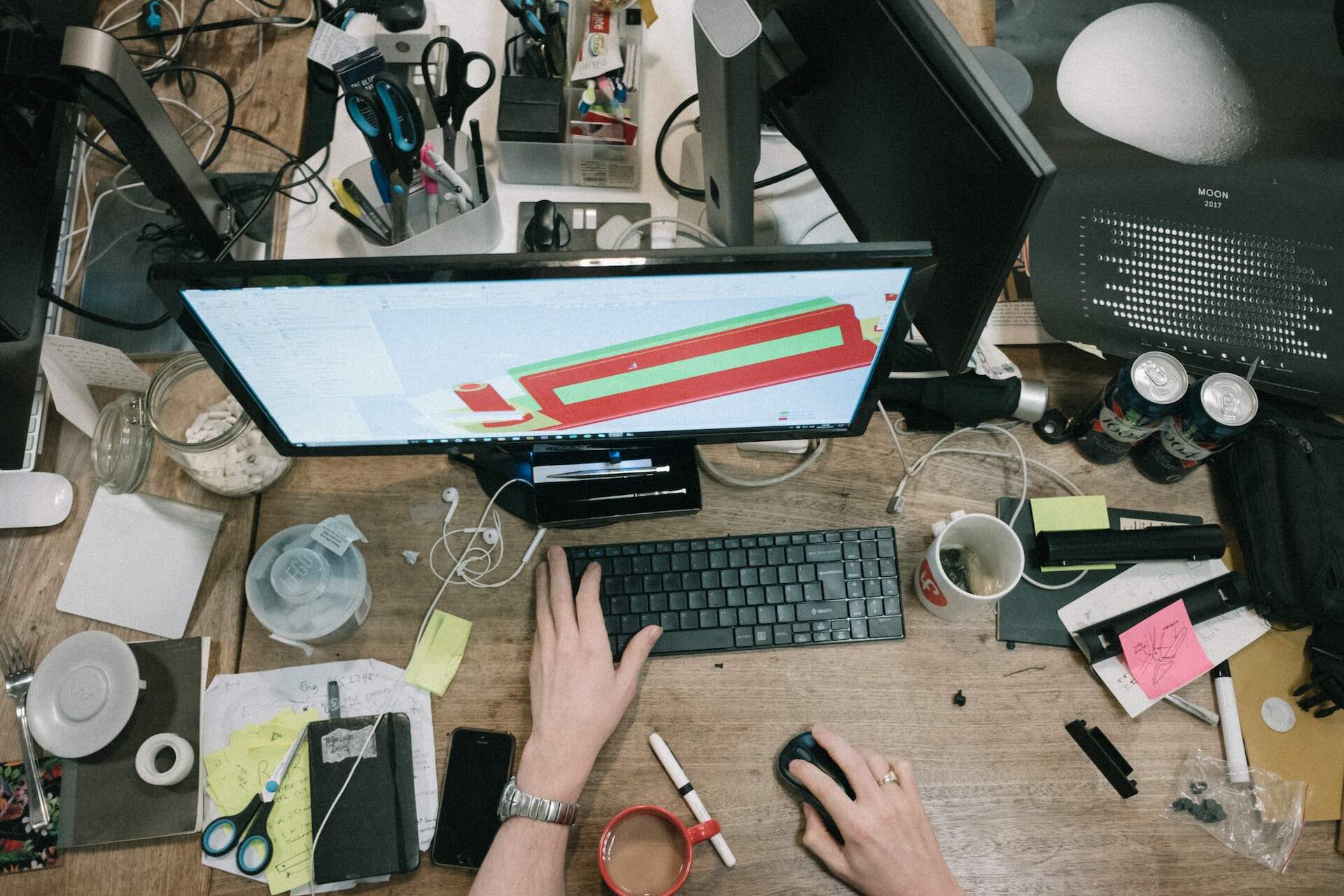 A person working at a computer overlooking a cluttered desk